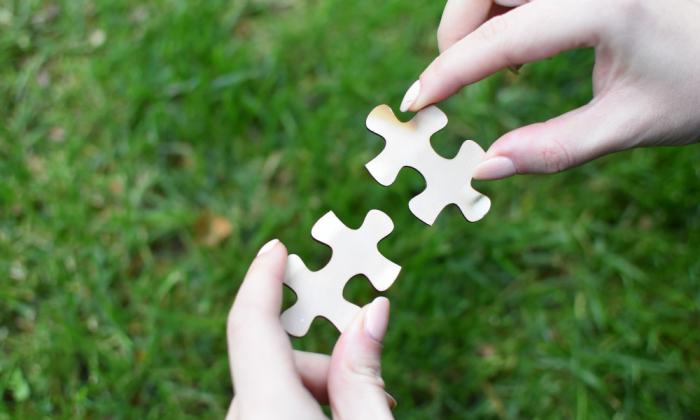 Photo of two hands putting puzzle pieces together