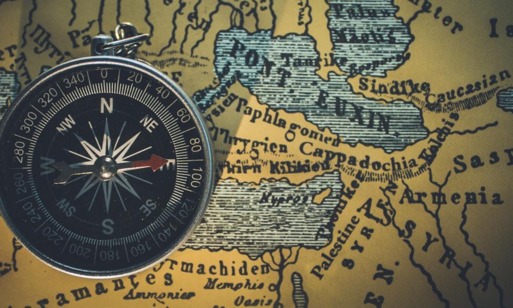 Small compass laying on a map for direction