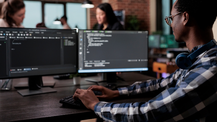 Developer coding on two computer screens