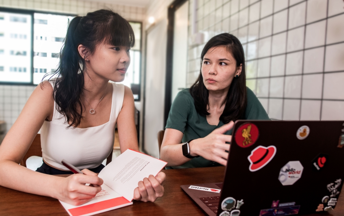 Duas associadas da Red Hat conversando e fazendo anotações