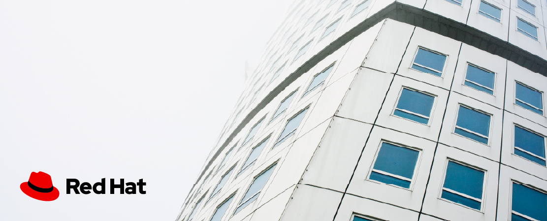 Image of a building with the Red Hat logo placed in the bottom right corner where it is clear and has good contrast against the white background.