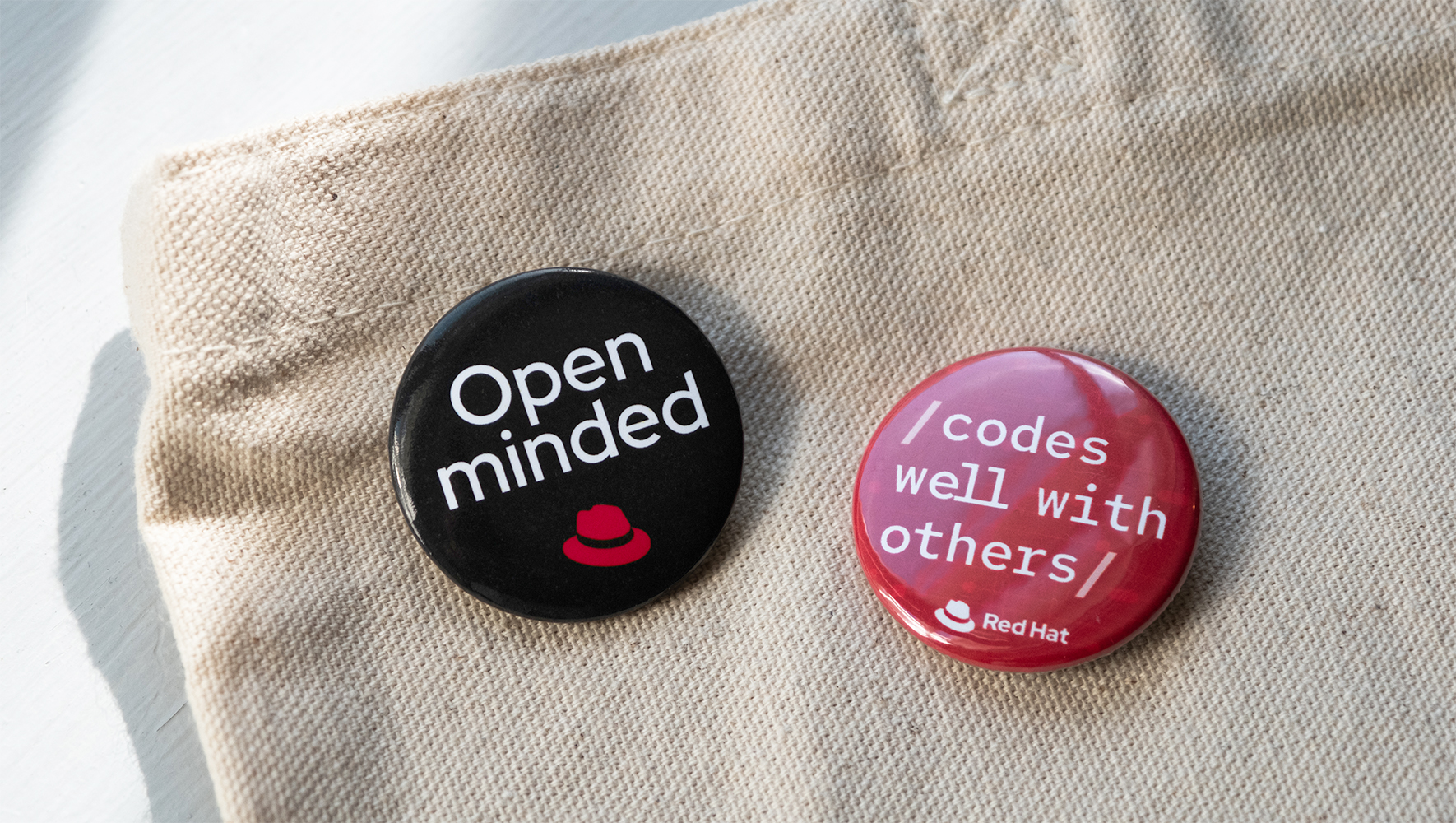 Two buttons pinned on a tote bag. The first button has the text 