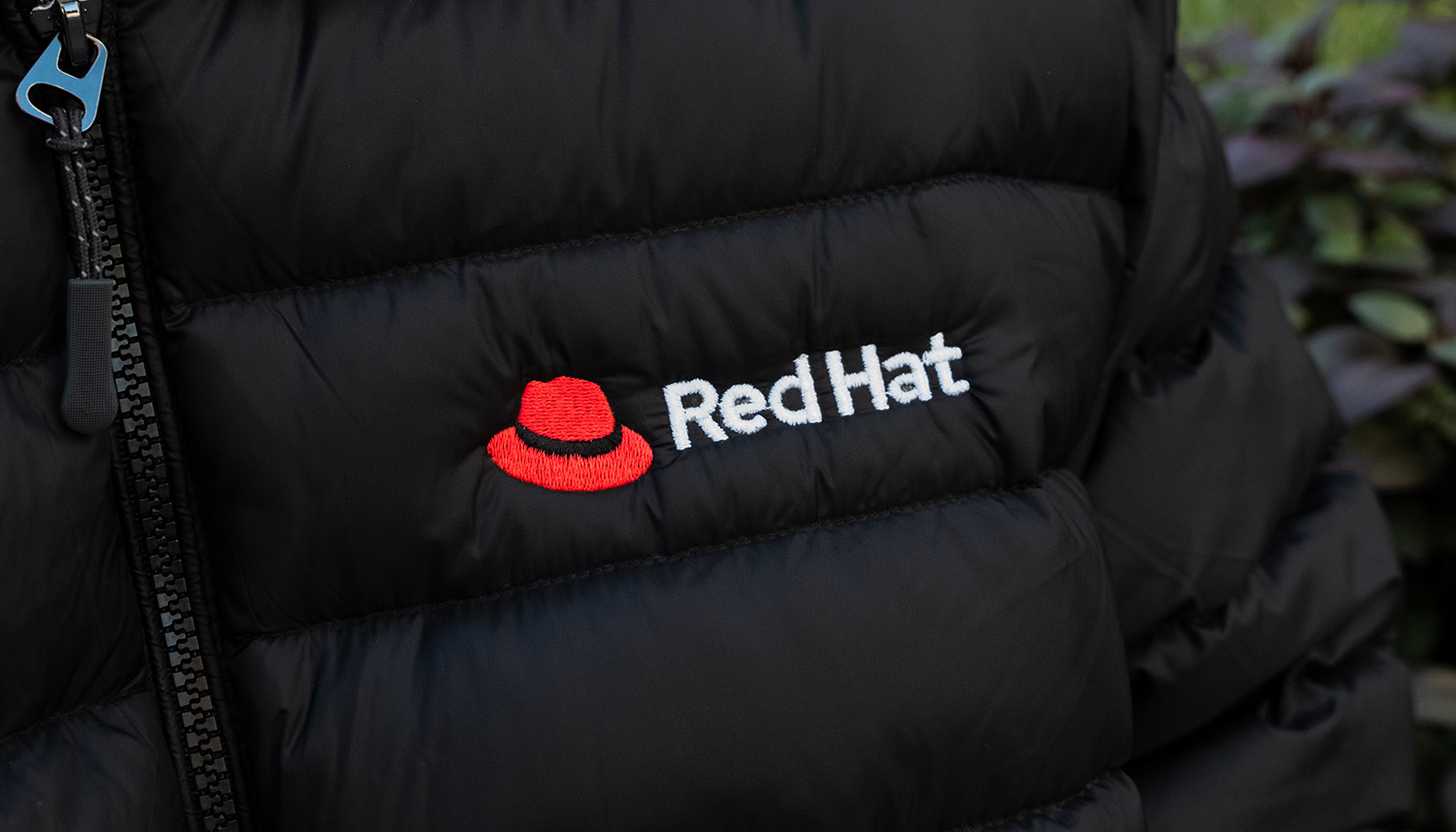 The Red Hat logo embroidered on a black puffer jacket.