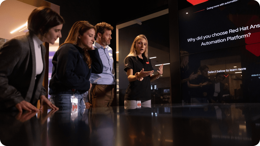 A small group of people gather around a large screen