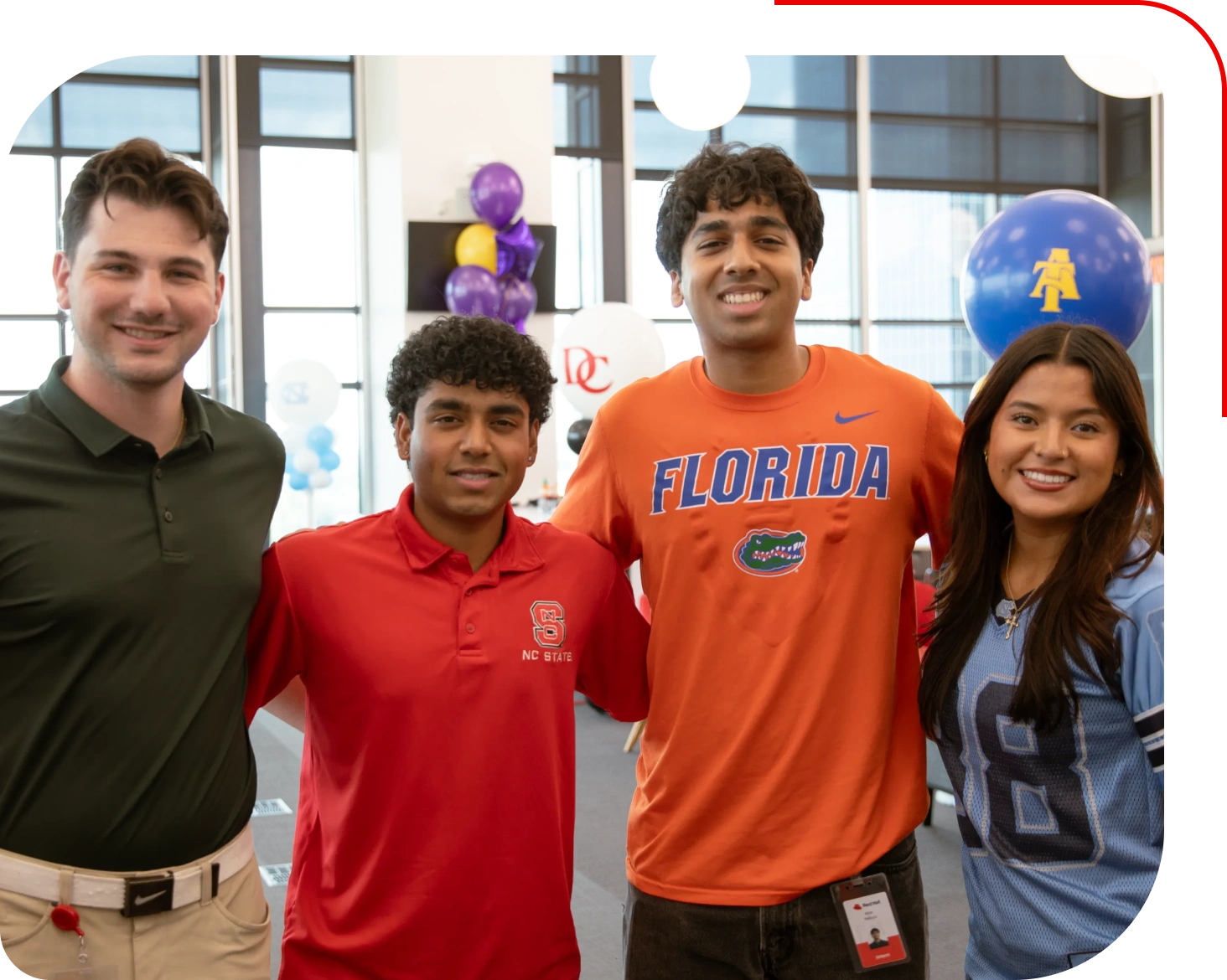 Four smiling young adults posing together during an indoor event