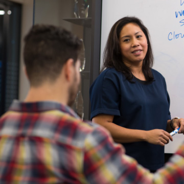 GSI-Partner entwerfen skalierbare Infrastruktur an einem Whiteboard. Der schreibende Partner hört dem anderen zu