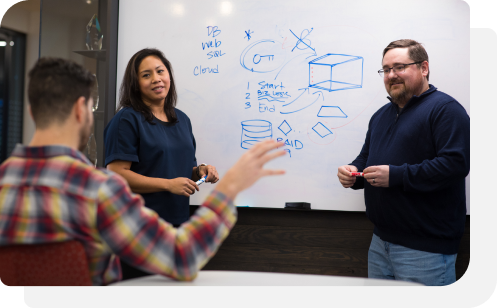 Three colleagues collaborating at a whiteboard during a brainstorming session