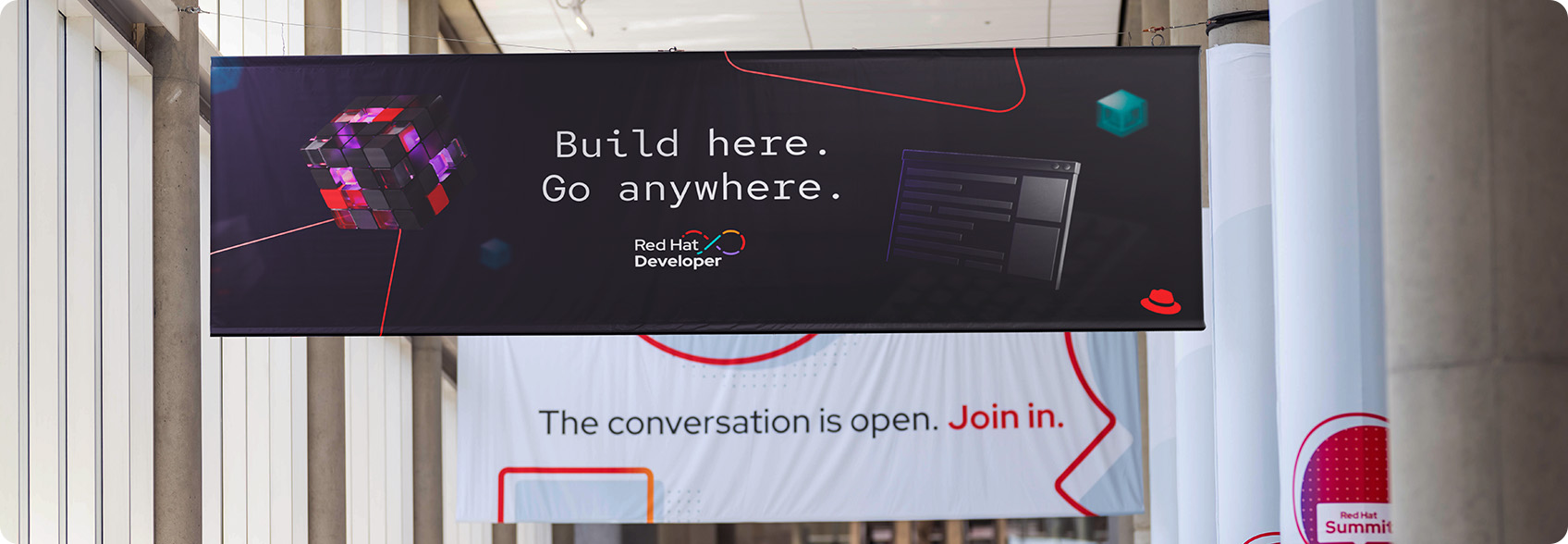 A banner hanging in a convention center advertising Red Hat Developer.