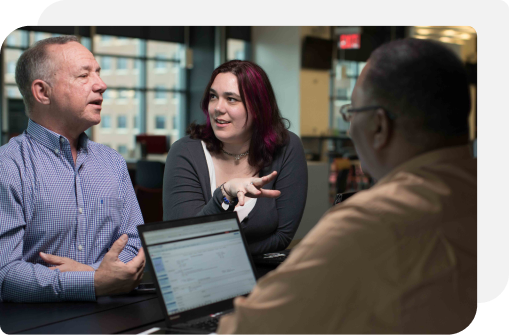 Three colleagues collaborating around a laptop in an office setting