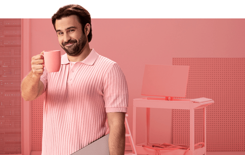 homem segurando um notebook embaixo do braço e uma caneca como se dissesse "saúde!"