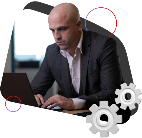 A focused man in a suit works on a laptop
