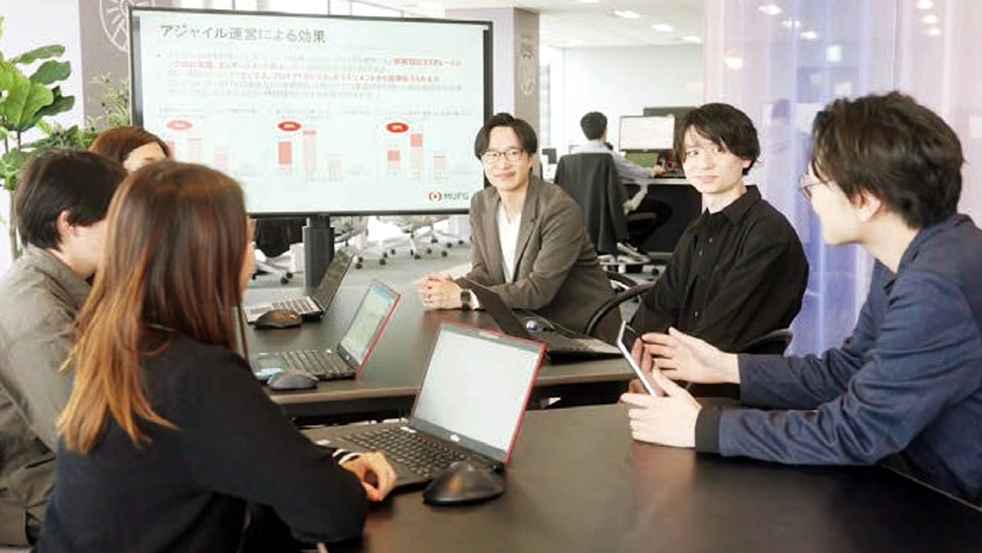 A team of colleagues collaborates in a conference room with a presentation on a large screen