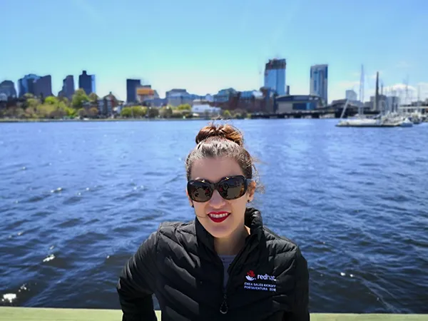 Pilar Bravo wearing a Red Hat jacket in front of a city skyline