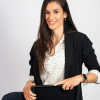 Professional portrait of a smiling woman with long brown hair, wearing a blazer and polka-dot blouse