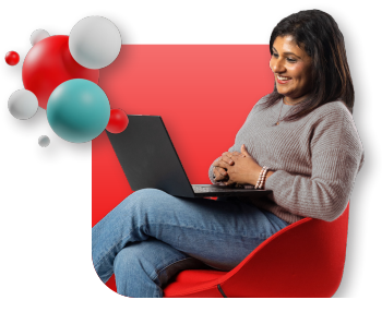 A woman in a red chair smiles at her laptop, with spheres floating above