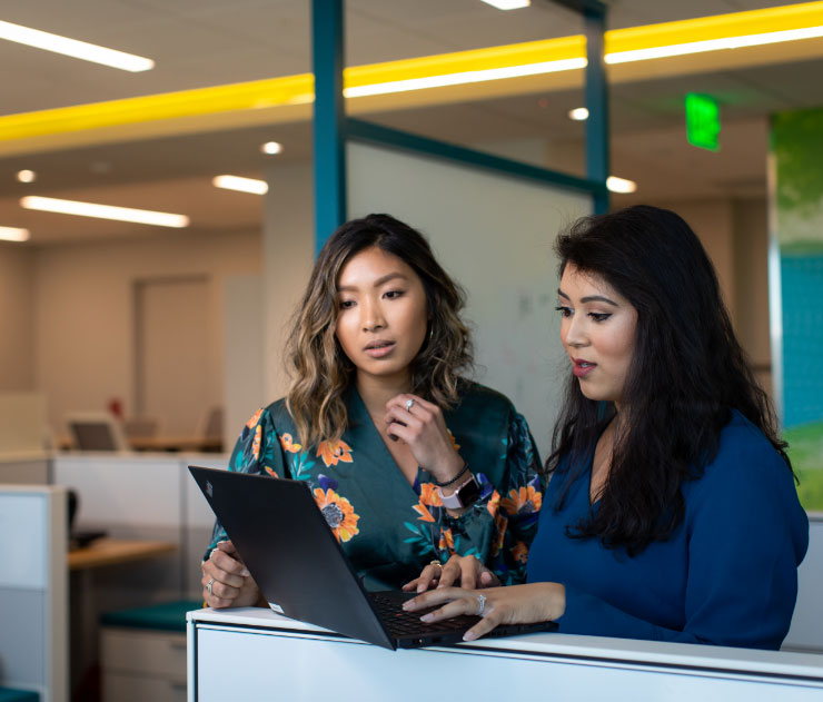 Compañeras de trabajo mirando una computadora portátil