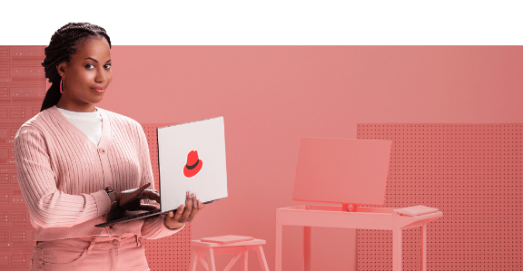 Woman looks up from typing on a Red Hat laptop and smiles confidently.