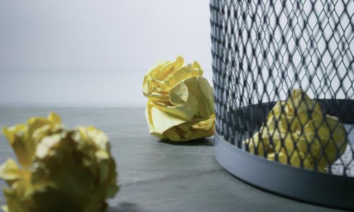 Crumpled yellow paper with a metal trash basket